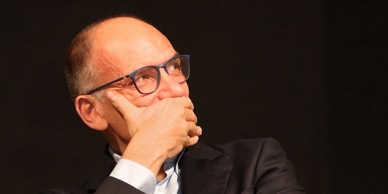 Un político se cubre la boca mientras escucha a otra persona.