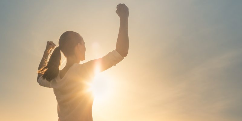 Mujer levantando los brazos representándo el concepto de poder femenino.