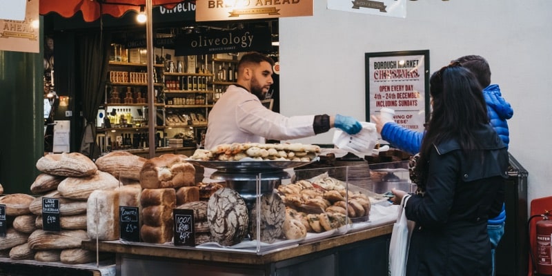 Una mujer compra bienes de consumo en un puesto de pan.