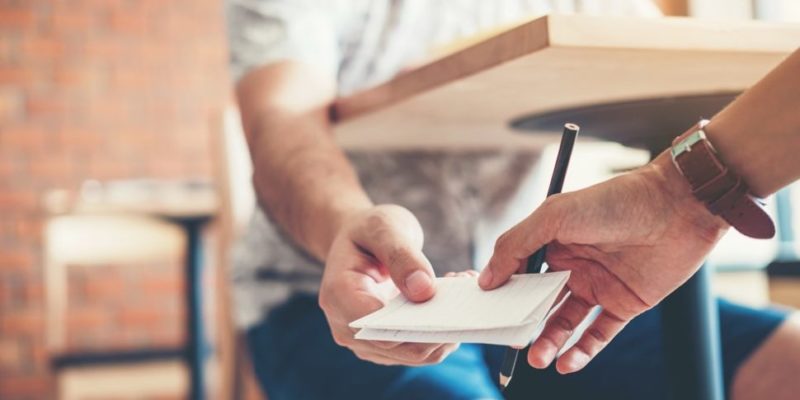 Dos estudiantes se pasan un papel con un mensaje escrito.