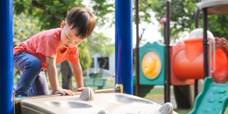 Un niño trepa en un juego en un parque