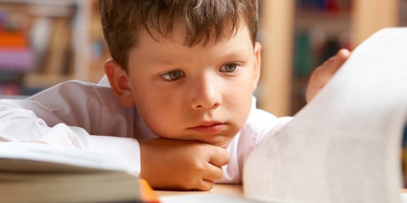 Un niño mira un libro con atención.