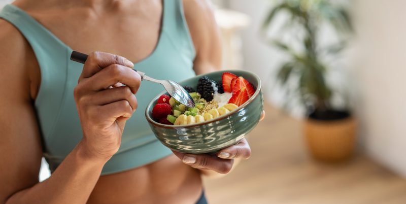 Mujer sosteniendo bowl de yogurt con frutas.