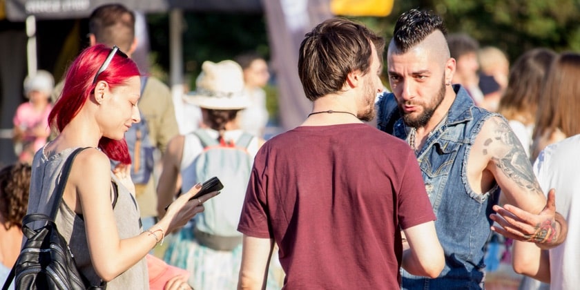 Dos personas utilizan la comunicación directa al hablar mientras otra utiliza la comunicación indirecta a través de un teléfono.