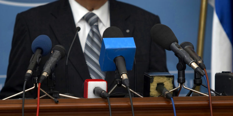 Un hombre habla frente a los micrófonos de la prensa