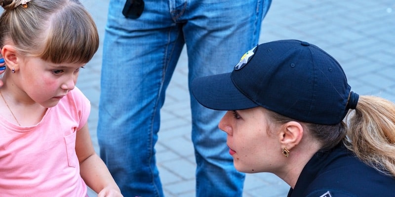 Una mujer policía habla con una niña pequeña.