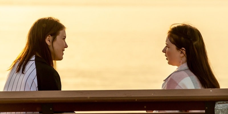 Dos amigas hablan en privado de un asunto confidencial.