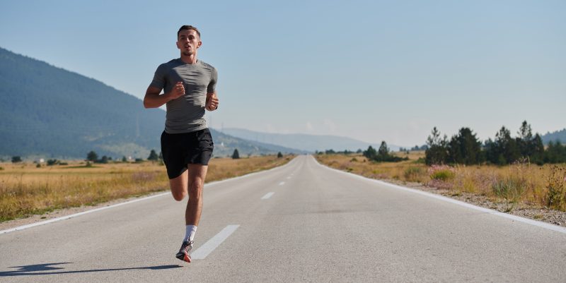 Hombre corriendo en un camino de pavimento.