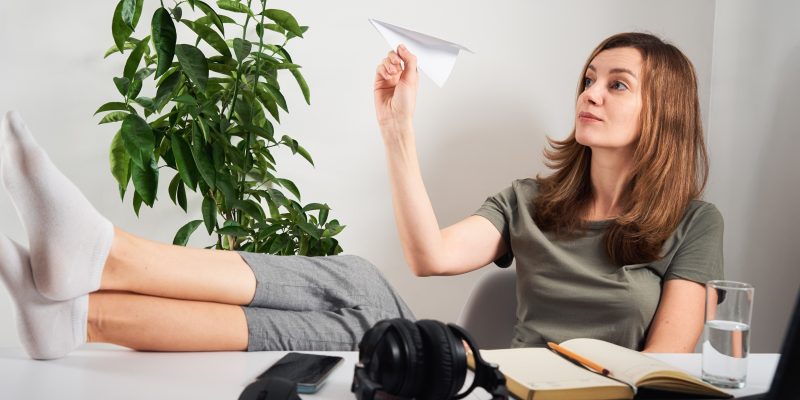 Mujer en su oficina jugando con un avión de papel.
